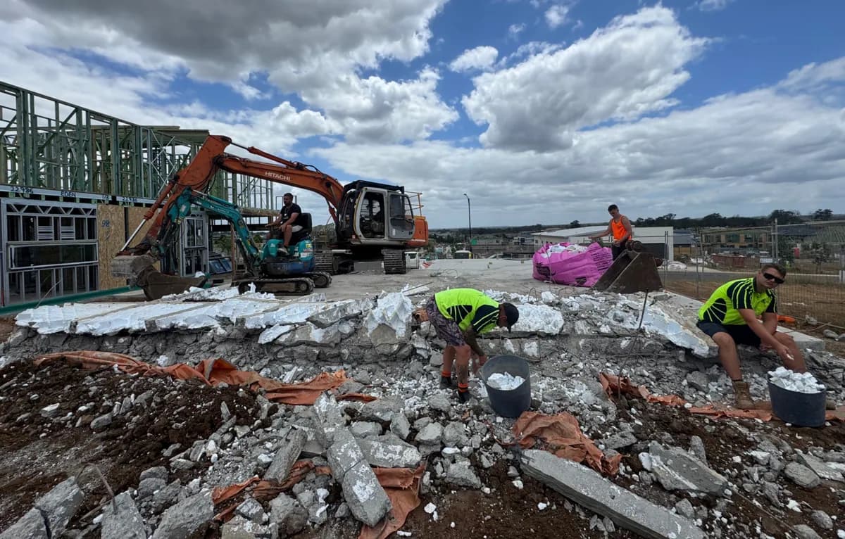 AJ excavator working on a broken concrete waffle-pod slab with separated foam and concrete