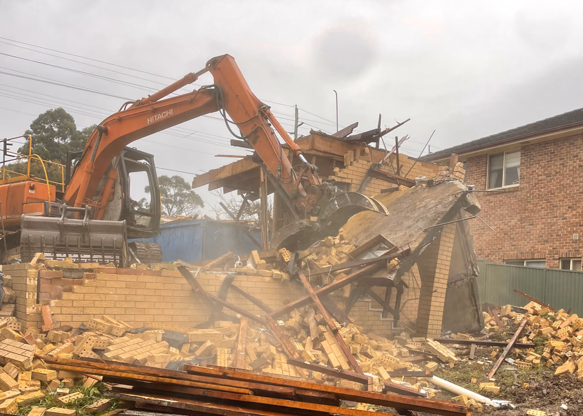 AJ excavator separating building materials during residential demolition