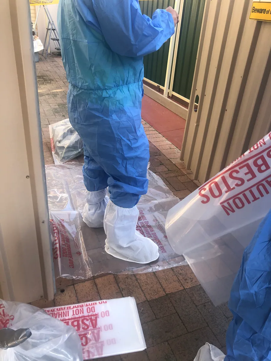 AJ worker in protective clothing preparing materials within a removal work area